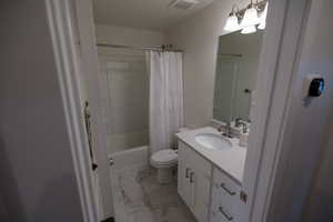 Full bathroom with toilet, vanity, and shower / bathtub combination with curtain