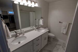 Bathroom featuring toilet, vanity, and a shower with curtain