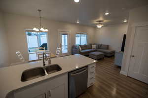 Kitchen with sink, white cabinets, decorative light fixtures, dishwasher, and ceiling fan with notable chandelier