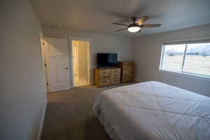 Bedroom with ensuite bath, ceiling fan, and light colored carpet