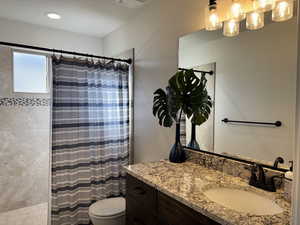 Bathroom featuring a shower with curtain, toilet, and vanity