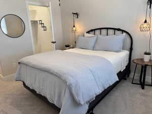 Bedroom featuring a walk in closet, a closet, and light carpet