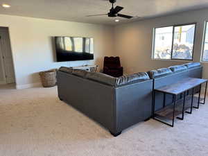 Living room featuring ceiling fan, light colored carpet, and a textured ceiling