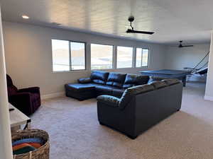 Carpeted living room featuring a textured ceiling, ceiling fan, and a mountain view