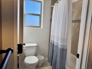 Bathroom featuring shower / tub combo with curtain and toilet