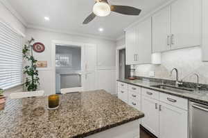 Kitchen with white cabinets, sink, dishwasher, and stone countertops