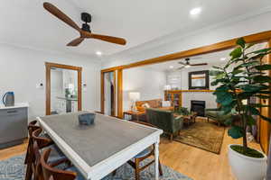 Dining area with a fireplace, light hardwood / wood-style floors, and ornamental molding