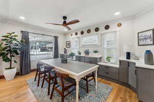 Dining room featuring ceiling fan, plenty of natural light, tons of cabinets, and light hardwood / wood-style flooring