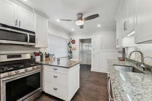 Kitchen featuring light stone counters, white cabinetry, sink, and appliances with stainless steel finishes