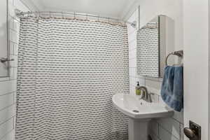 Bathroom featuring curtained shower, sink, and tile walls