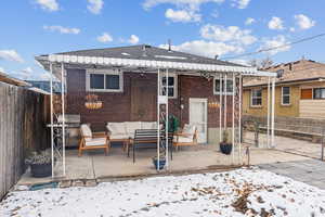 Snow covered back of property with outdoor lounge area and a patio