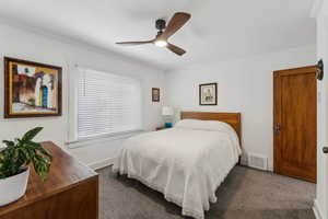 Primary bedroom featuring ceiling fan, dark carpet, and crown molding