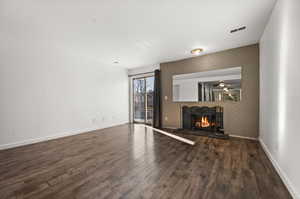 Unfurnished living room featuring ceiling fan and dark wood-type flooring