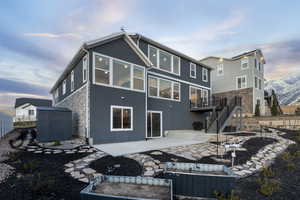 Rear view of house featuring a storage unit, patio, & deck