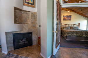 Bedroom featuring wooden ceiling, a tiled fireplace, and vaulted ceiling