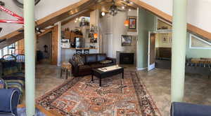 Living room with ceiling fan, high vaulted ceiling, and fireplace