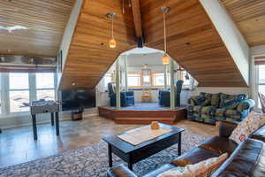 Living room with beam ceiling, high vaulted ceiling, loads natural light, and wooden ceiling