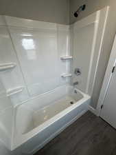 Bathroom with hardwood / wood-style flooring and washtub / shower combination