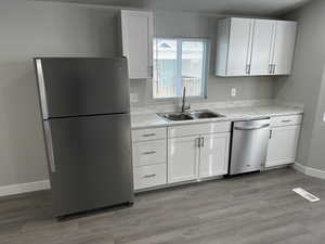 Kitchen with appliances with stainless steel finishes, white cabinetry, and sink