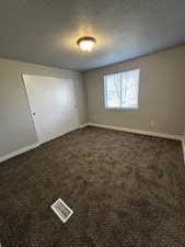 Carpeted empty room featuring a textured ceiling