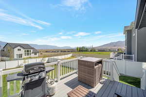 Wooden deck with a grill, a mountain view, and a lawn