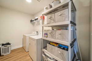 Laundry room with separate washer and dryer and light wood-type flooring