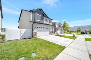 View of front facade featuring a front lawn, a garage, and a mountain view