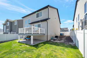 Back of house featuring a yard, central AC unit, a wooden deck, and a patio