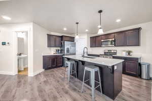 Kitchen with pendant lighting, stainless steel appliances, an island with sink, a kitchen breakfast bar, and sink