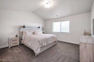 Bedroom featuring lofted ceiling and dark carpet