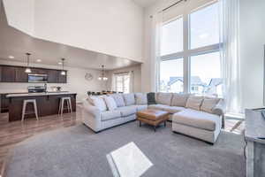 Living room with a towering ceiling, a chandelier, and light hardwood / wood-style flooring