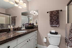 Bathroom with a shower with door, vanity, and toilet