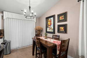 Tiled dining room with a chandelier and vaulted ceiling