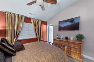 Carpeted bedroom featuring ceiling fan and vaulted ceiling