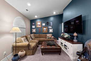 Carpeted living room featuring lofted ceiling