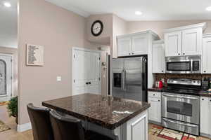 Kitchen with white cabinetry, a breakfast bar, stainless steel appliances, and vaulted ceiling