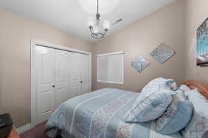 Bedroom featuring a closet, carpet, a chandelier, and lofted ceiling