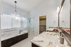 Master bath featuring large window above jetted tub, double vanity, vaulted ceiling, walk-in shower and closet