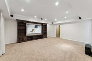 Carpeted home theater room with a raised ceiling and surround sound