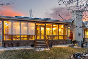 Back house at dusk featuring an enclosed deck with skylights and retractable shades