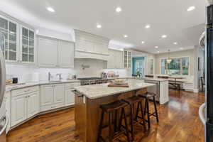 Kitchen featuring a prep sink, breakfast bar, a center island, hardwood  flooring and white cabinetry