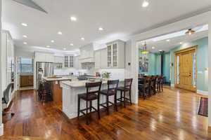 Kitchen with tile backsplash, light granite countertops, stainless steel appliances, white cabinetry, a prep sink and a breakfast bar