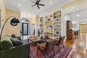 Living room featuring built in book shelves, crown molding and ceiling fan