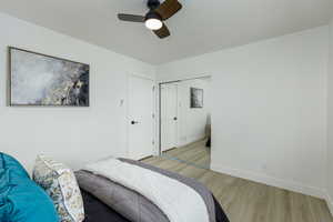 Bedroom featuring ceiling fan, light hardwood / wood-style floors, and a closet