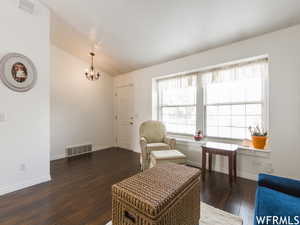 Living area with lofted ceiling, dark hardwood / wood-style flooring, and a notable chandelier