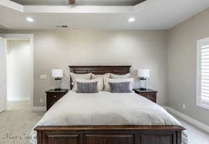 Bedroom featuring light colored carpet, a raised ceiling, and multiple windows