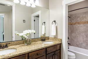 Full bathroom with toilet, vanity, and tiled shower / bath combo