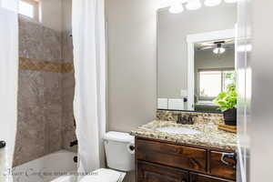 Full bathroom with toilet, vanity, ceiling fan, and shower / bathtub combination with curtain