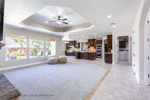 Living room featuring a raised ceiling, ceiling fan, and washer and clothes dryer