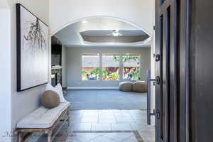 Hallway with a tray ceiling and light colored carpet